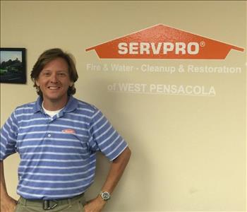 Male owner with light brown hair standing in front of a SERVPRO logo for West Pensacola.
